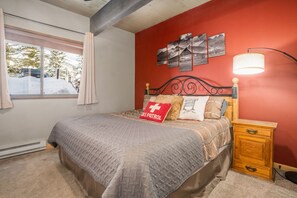A bedroom with a bed, a nightstand, a lamp, and a window with curtains.