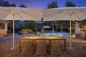 An outdoor dining area with a pool, surrounded by lounge chairs and umbrellas. - Can Verd (Pollensa)