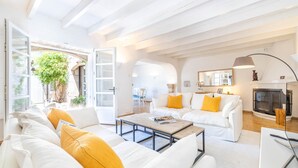 A spacious living area with white furniture, a fireplace, and a view of the outdoors. - Can Verd (Pollensa)