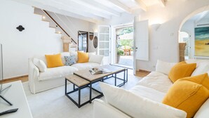 A spacious living room with a white sofa set, a wooden coffee table, and a staircase leading to an outdoor area. - Can Verd (Pollensa)
