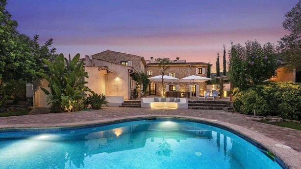 A swimming pool with a stone deck, a stone building with a tiled roof, and outdoor seating with umbrellas. - Can Verd (Pollensa)