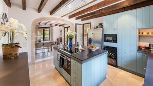 Une cuisine moderne dotée d’un îlot central, d’appareils électroménagers intégrés et d’une arche en pierre menant à un coin repas.