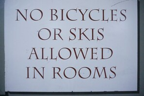 Een bord met de tekst: 'FIETSEN EN SKIËN ZIJN NIET TOEGESTAAN IN DE KAMERS'.
