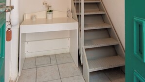 A staircase with a wooden handrail and a white wall with framed pictures and a shelf. - Dina house (Lakka)