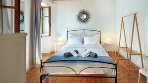A neatly arranged bedroom with a bed, bedside tables, a hanging light fixture, and a mirror on the wall. - Dina house (Lakka)