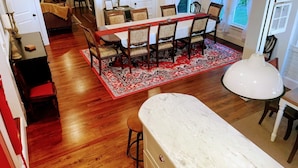 A spacious dining area with a long table, multiple chairs, and a red patterned rug. - The Flowers House - Downtown Historic Home in the Heart of Mount Dora (Mount Dora)