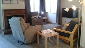Een woonkamer met een open haard, een televisie en een bank.