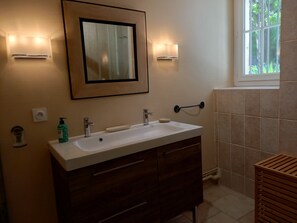 A bathroom with a white sink, dark wooden vanity, a framed mirror, and two wall-mounted lights.
