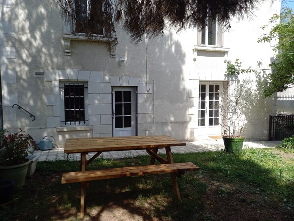 A wooden bench in front of a building with a white exterior, a window, and a door.