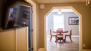 A dining area with a round table and chairs, a ceiling fan, and a window with natural light. - Holland Suites, Suite #4 (Williamstown)