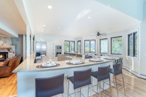Una cocina amplia con una isla grande, electrodomésticos modernos y abundante luz natural proveniente de amplios ventanales.