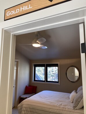 A bedroom with a bed, a ceiling fan, a window, and a mirror.