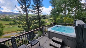 A hot tub on a deck with a view of a green landscape and mountains.