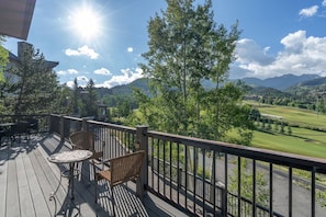 Eine Terrasse mit Gartenmöbeln mit Blick auf einen Golfplatz und Berge.