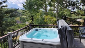 A hot tub on a deck with a view of a forest and mountains. - 226 Country Club Dr 5 Bedroom House (Mountain Village)