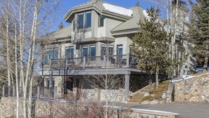 A multi-story house with a stone facade, a balcony, and a stone staircase leading to the entrance. - 226 Country Club Dr 5 Bedroom House (Mountain Village)