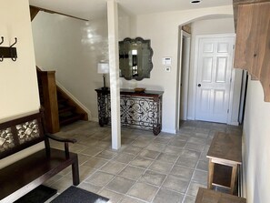 A hallway with a wooden bench, a decorative mirror, a small table, and a door. - 226 Country Club Dr 5 Bedroom House (Mountain Village)