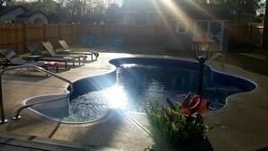 Un jardin avec une piscine, des chaises longues et une clôture en bois.