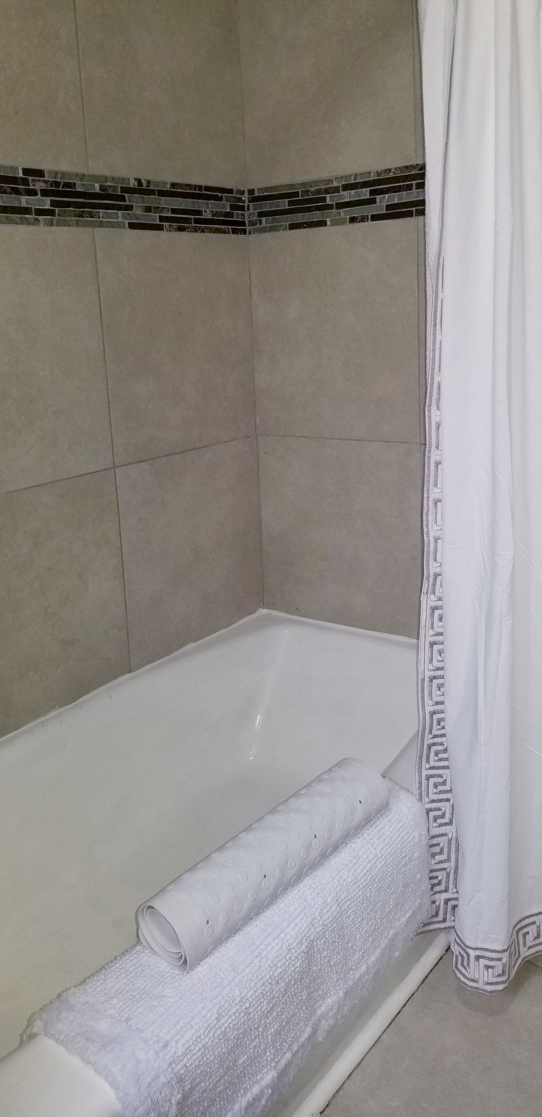A bathroom with a bathtub, a towel, and a shower curtain.