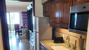 A kitchen with granite countertops, a stainless steel refrigerator, and wooden cabinets.