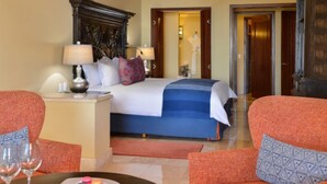 A hotel room with a bed, two bedside tables, a nightstand, a chair, a table with a glass, and a ceiling fan.