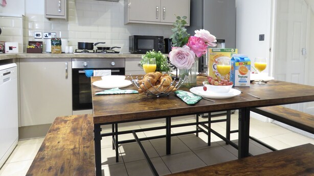 Een moderne keuken met een ontbijttafel, compleet met croissants, fruit en een fles sinaasappelsap.