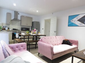 Une cuisine moderne avec un coin repas, comprenant un canapé rose et une petite table.