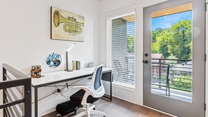 Um espaço de escritório moderno com uma mesa, cadeira e obras de arte na parede.