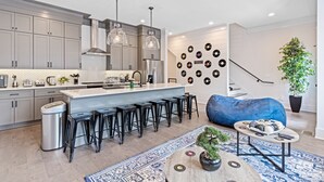 Uma cozinha moderna com armários cinza, uma ilha central com banquetas e uma parede decorada com discos de vinil.