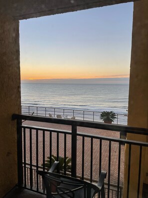 A balcony with a view of the sea at sunset. - Oceanfront Retreat- Steps from the Beach & Great Rates (Myrtle Beach)