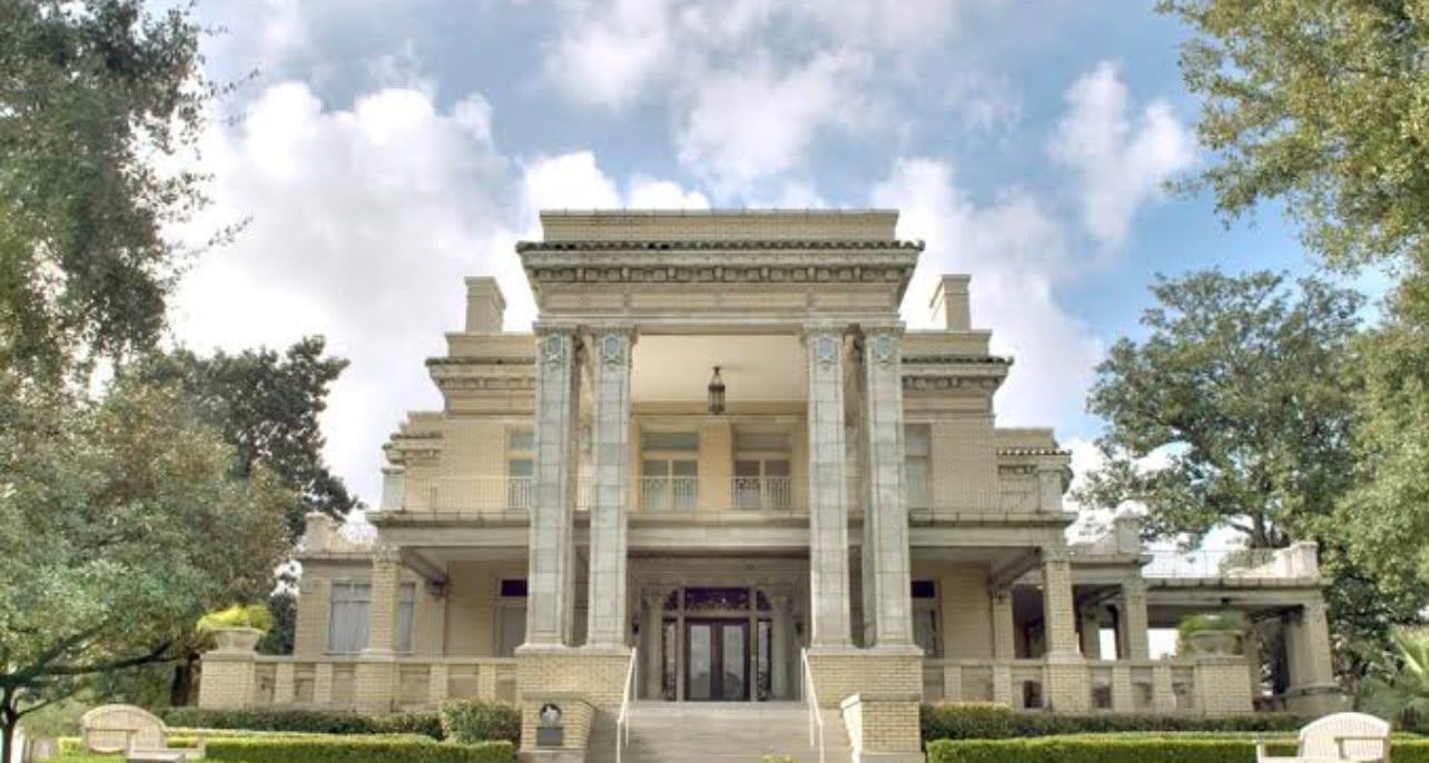 Un grand bâtiment imposant, doté d’une façade symétrique, de colonnes saillantes et d’une entrée centrale.