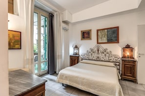A bedroom with a bed, a desk, a window with curtains, and two wall-mounted lamps.