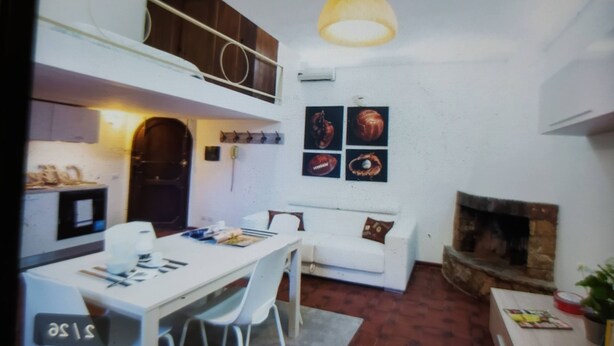 A compact living space with a dining area, a sofa, a fireplace, and a kitchen area with a hanging light fixture. - A Roma Trastevere (Roma)