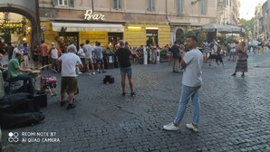 Une rue animée où l’on aperçoit un bar appelé « Bar S.Calisto » et une foule de personnes.