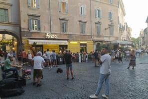 Eine belebte Straßenszene mit einer Bar namens 'Bar S.Calisto' und einer Menschenmenge.