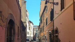 A narrow cobblestone street flanked by buildings with arched doorways and balconies. - A Roma Trastevere (Roma)