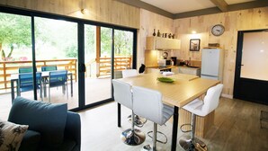 A modern kitchen with a wooden countertop, white bar stools, and a dining area with a table and chairs. - HOUSE WITH AIR CONDITIONING (Doucier)