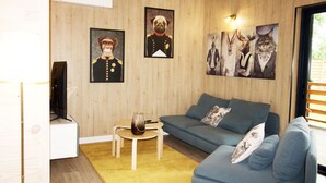 A living room with a blue sofa, a small wooden table, and a yellow rug. There are framed pictures on the wall. - HOUSE WITH AIR CONDITIONING (Doucier)