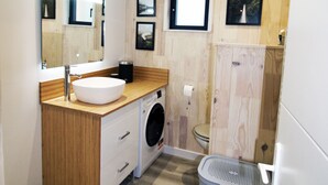 A modern bathroom with a wooden vanity, a sink, a washing machine, and a toilet. - HOUSE WITH AIR CONDITIONING (Doucier)