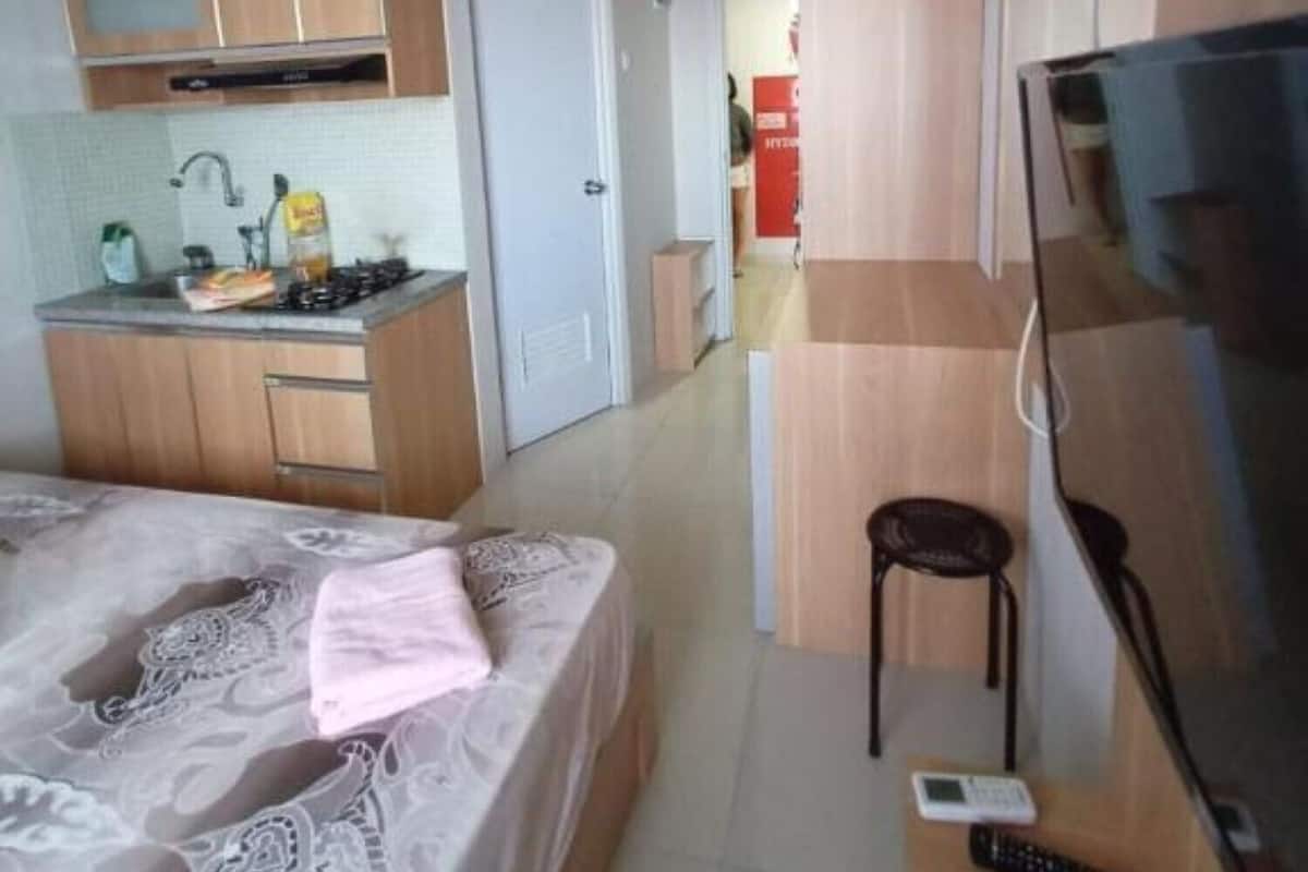 Een compacte hotelkamer met een kitchenette, een bed, een televisie en een klein tafeltje met een stoel.