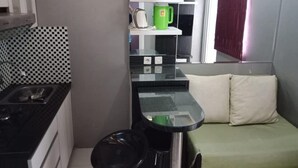 Eine kleine Küche mit schwarzem Arbeitsplatz, einer Spüle und einem grünen Wasserkocher auf einem Regal.