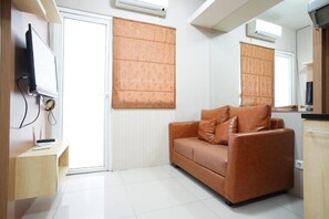 Un salon moderne avec un canapé en cuir, un téléviseur à écran plat fixé au mur et une porte coulissante dotée d’un store en bambou.