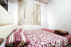 Une chambre à coucher avec un lit, une fenêtre avec des rideaux et une serviette sur le lit.
