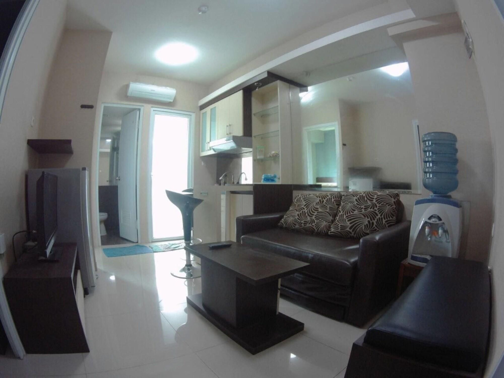 A living room with a sofa, coffee table, TV, and a water dispenser.