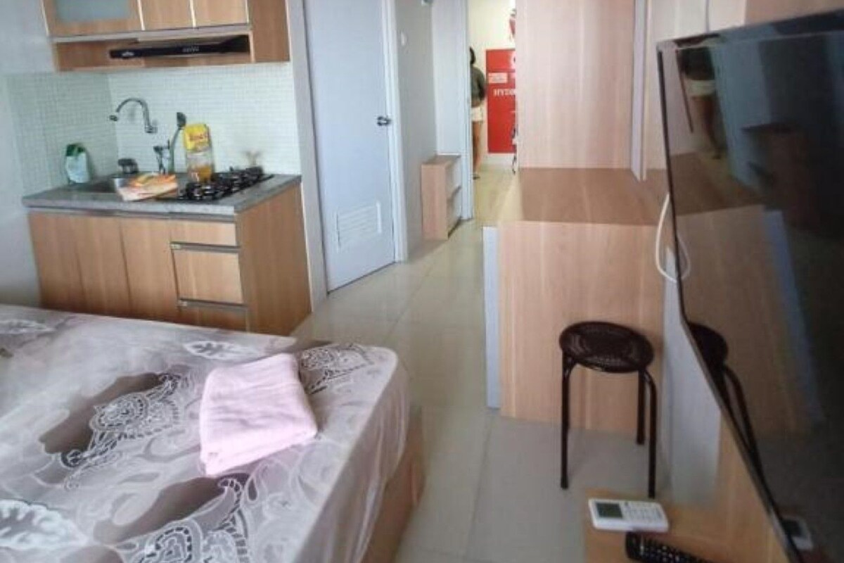 Une chambre d’hôtel compacte comprenant un coin cuisine, un lit, une télévision et une petite table avec une chaise.
