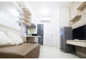 Ein kleines Hotelzimmer mit Bett, einem Schreibtisch mit Fernseher und einem Kleiderschrank.