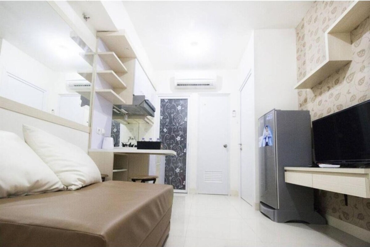 Ein kleines Hotelzimmer mit Bett, einem Schreibtisch mit Fernseher und einem Kleiderschrank.
