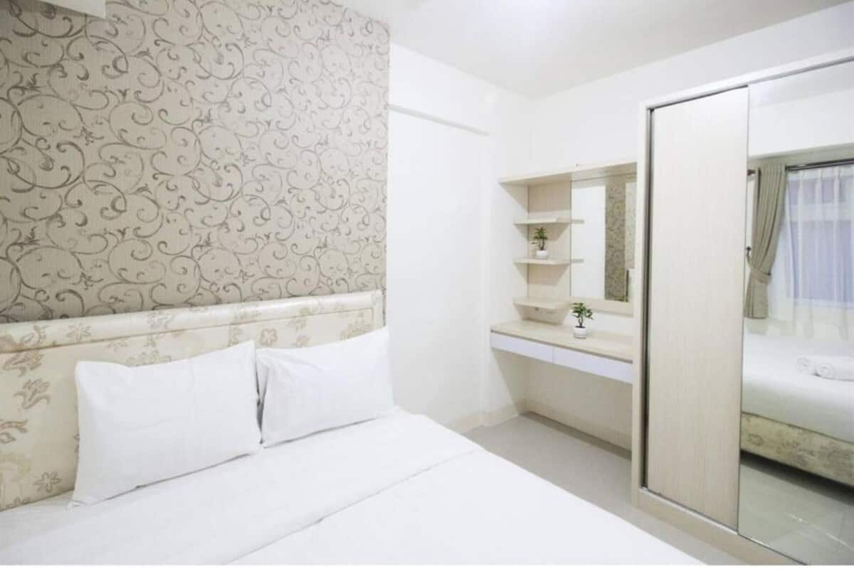 Hotelkamer met een bed, nachtkastje met spiegel, garderobe en badkamer met douche.