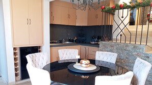 A modern kitchen with wooden cabinets, a black countertop, and a dining area with a round table and four chairs. - Departamento Villa Neek (San Cristóbal de las Casas)