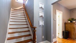 A staircase with wooden steps and a wooden handrail, leading to a landing with three framed cityscape pictures on the wall.